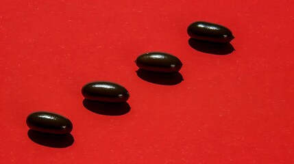 Four dark pills on a vibrant red surface forming a descending diagonal line