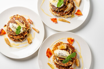 Cottage cheese pancakes with cream cheese, orange, honey and mint on a white plate and background. Healthy, dietary breakfast. Top view