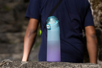 Reusable flavored water bottle in foreground with man in background for outdoor hydration and...
