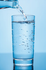 Crystal clear water being poured into a transparent glass, creating refreshing ripples and bubbles
