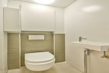 A sleek and minimalistic bathroom featuring clean lines, a wall-mounted toilet, and a compact sink. The light color palette enhances the spacious look.