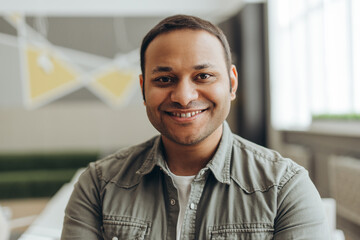 Portrait of smiling indian businessman standing in modern office