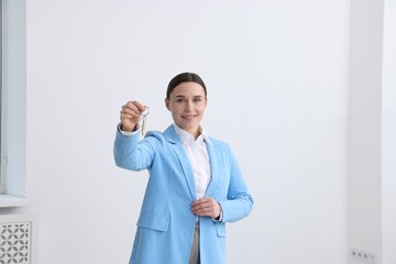 Real estate agent holding key with house shaped keychain indoors