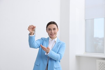 Real estate agent holding key with house shaped keychain indoors