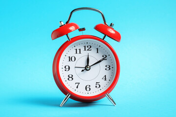 One red alarm clock on light blue background