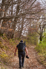 Naklejka premium Hiker walking uphill on forest trail with backpack and camera