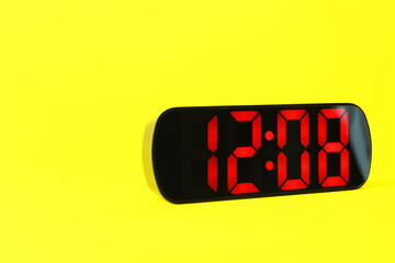 Digital alarm clock showing 12:08 o'clock on yellow background, space for text