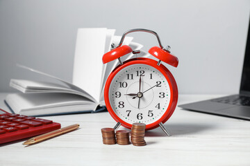 Alarm clock, coins, calculator, laptop and stationery on white wooden table. Tax time