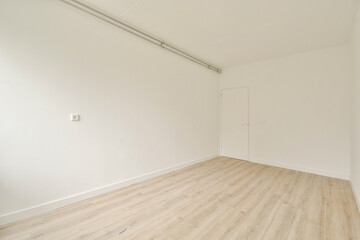 An unadorned and minimalist interior of an empty room showcasing light-colored walls and wooden flooring, creating a spacious and airy feel.