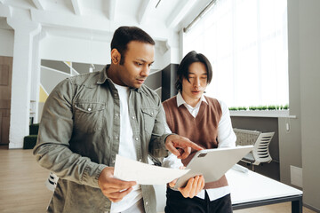 Marketing team analyzing data on digital tablet and documents