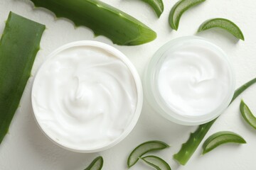 Moisturizing cream with extract of aloe vera and cut leaves on white textured background, flat lay