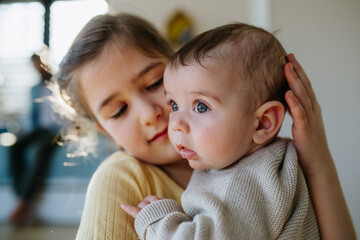 Big sister comforting sad baby brother.