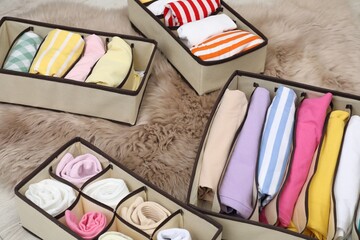 Organizers with folded clothes on faux fur indoors, closeup