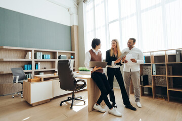 Business team discussing work in modern office using laptop and tablet