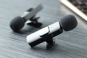 Lavalier microphones on black wooden table, closeup