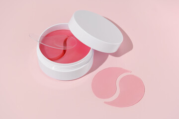 White jar with pink patches and spatula on pink isolated background with samplers. Concept of beauty and aesthetics care products, moisturizing skin under eyes, anti dark circles