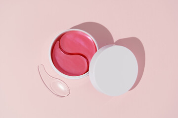Top view of white mockup jar with pink hydrogel patches and transparent spatula on pink isolated...