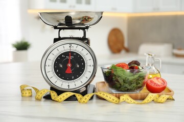 Kitchen scales, products and measuring tape on light marble table indoors