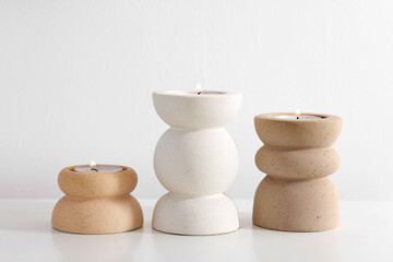 Stylish candlesticks with burning candles on white table