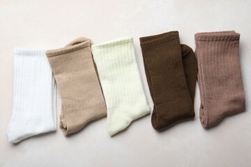 Different soft socks on light beige background, top view