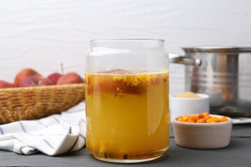 Tasty compot in glass jar and ingredients on grey wooden table, closeup