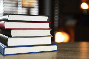 Stack of books on wooden table indoors, closeup. Space for text