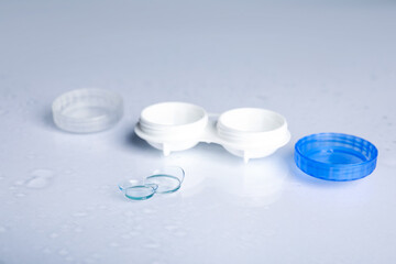 Pair of contact lenses and container on white mirror surface, closeup