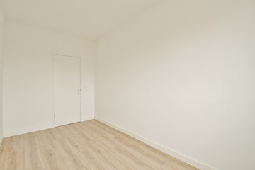 A spacious, minimalistic room featuring plain white walls, a wooden floor, and a single door. Ideal for modern design aesthetics and interior decoration inspiration.