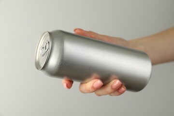 Woman with tin can on light grey background, closeup
