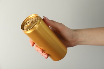 Woman with tin can on light grey background, closeup