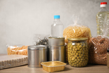 Different food products on wooden table against gray background