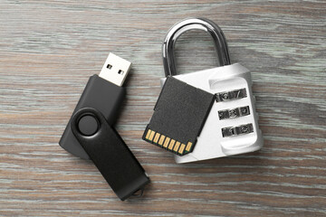 Flash drive, SD memory card and combination padlock on wooden background, flat lay