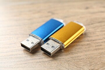 Two flash drives on wooden background, closeup