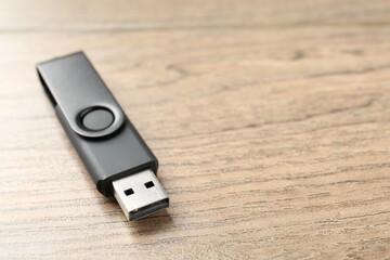 One flash drive on wooden background, closeup. Space for text