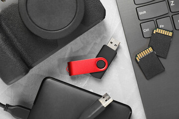 Flash drive, SD memory cards, external hard disk and camera on gray textured table, flat lay