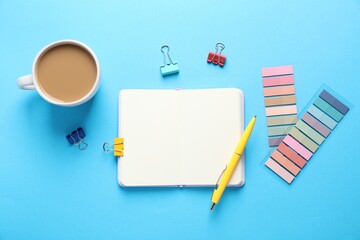 Open blank notebook, other stationery and coffee on light blue background, flat lay