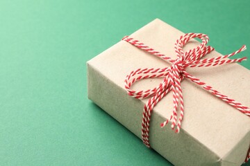 Gift wrapped in kraft paper with bow on green background, closeup. Space for text