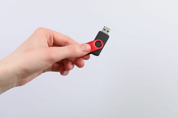 Man with modern flash drive on light grey background, closeup. Space for text