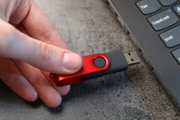 Man inserting modern flash drive at grey table, closeup