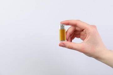 Man with modern flash drive on light grey background, closeup. Space for text