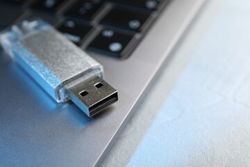 Flash drive and laptop on light grey table, closeup. Space for text