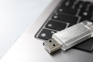 Flash drive and laptop on light grey table, closeup