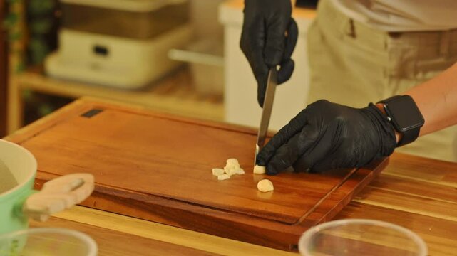 Slicing garlic on wooden cutting board during meal preparation