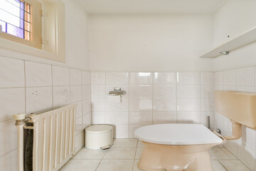 A minimalist bathroom featuring light-colored tiles, a modern toilet, and a stylish window. The space is bright and uncluttered, emphasizing simplicity.
