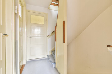 A well-lit interior hallway featuring a staircase, highlighting clean lines and warm tones throughout the design.