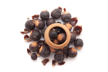 A mud pot filled with organic Soapnuts or Reetha (Sapindus mukorossi) is placed on a heap of Soapnuts berries, isolated on a white background.