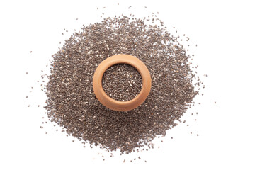 A mud pot filled with organic Chia Seeds (Salvia hispanica) is placed on a heap of Chia Seeds, isolated on a white background.