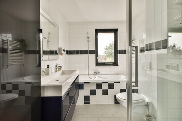 Stylish modern bathroom featuring sleek fixtures, a bathtub, and a chic black and white tile pattern that creates a contemporary ambiance.