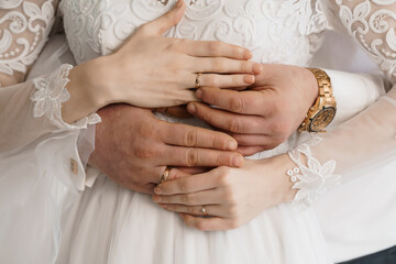 Hands Holding Together with Wedding Rings; a Close-Up Shot of a Couple's Intertwined Hands Displaying Golden Wedding Rings on White Lace Sleeves