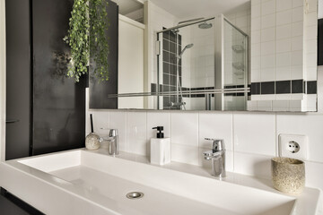 A sleek and contemporary bathroom showcasing a minimalist design with elegant fixtures, clean lines, and the addition of greenery for a refreshing touch.